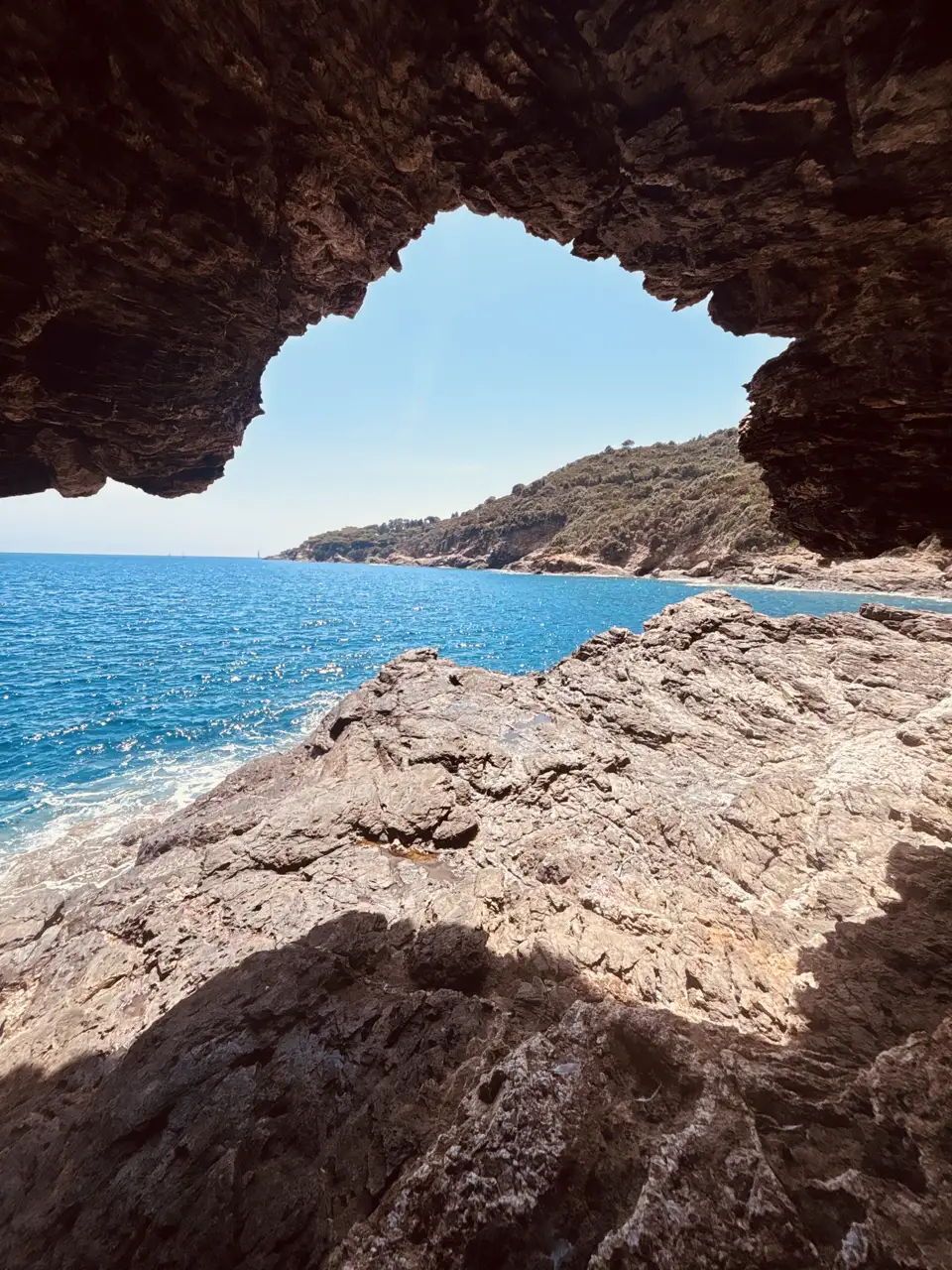 Blick aus einer Felshöhle heraus aufs offene Meer; der Höhlenrand rahmt Wasser und Felsküste.